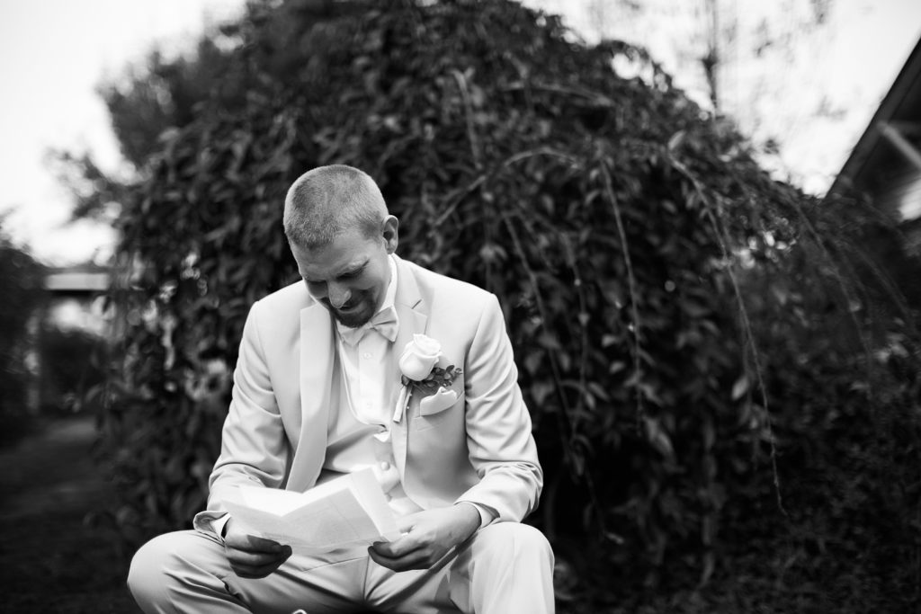 Groom reading letter from his to soon-to-be bride while getting ready. Photographed by Megan Montalvo Photography. 