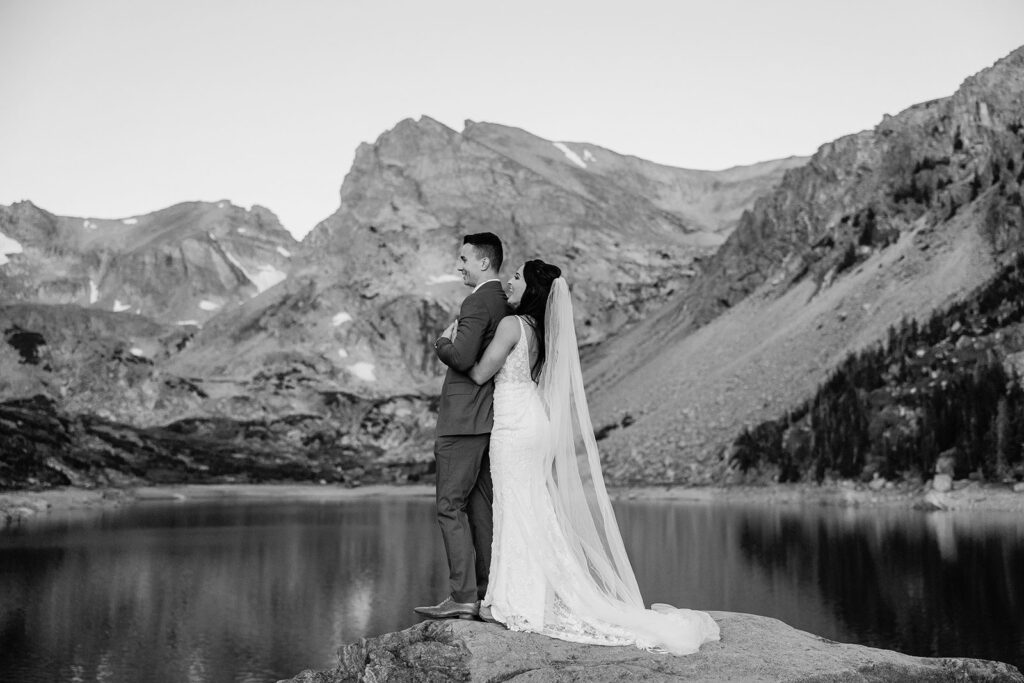 bride and groom kiss in front of lake
