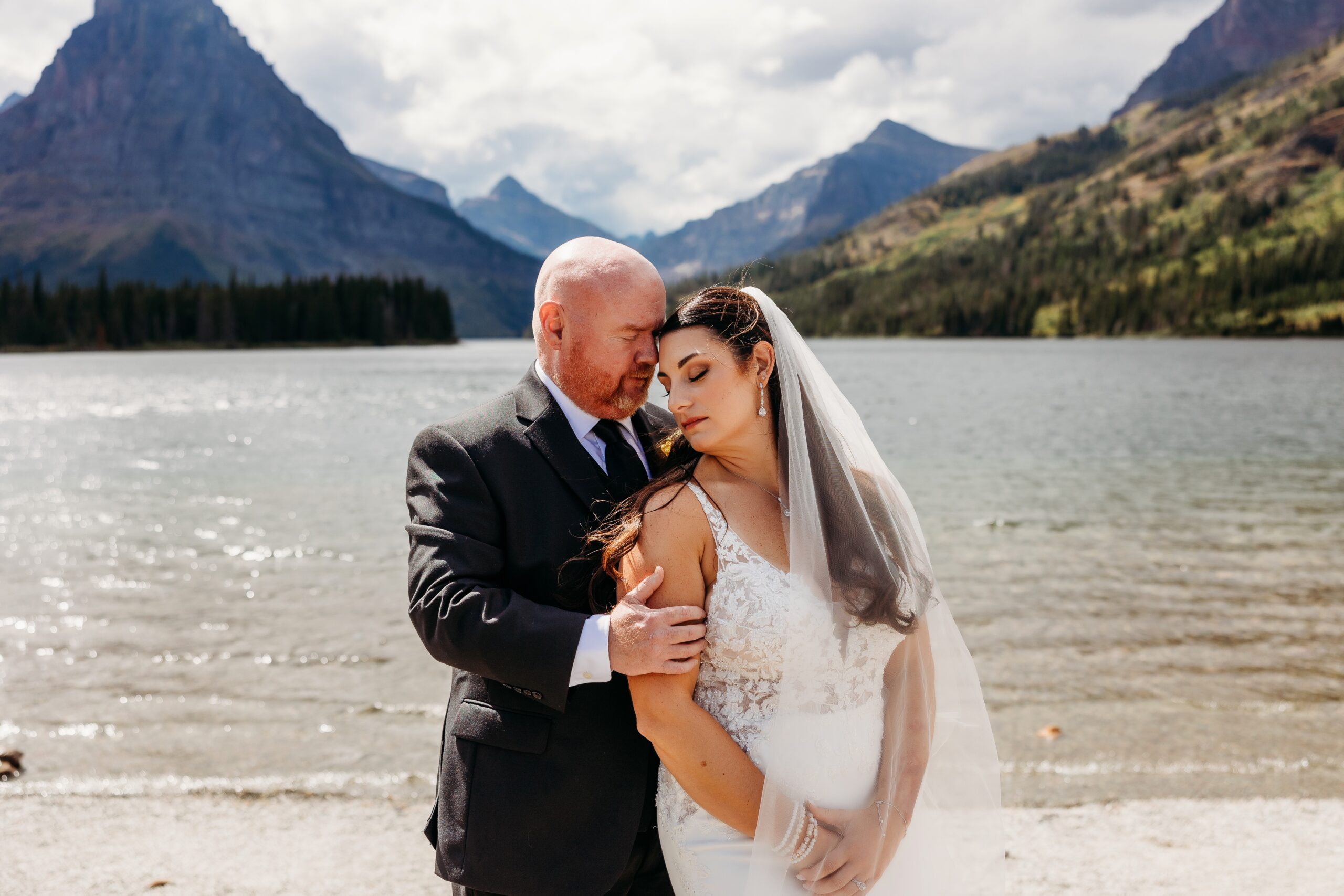 groom holds brides face in front of prayer lake