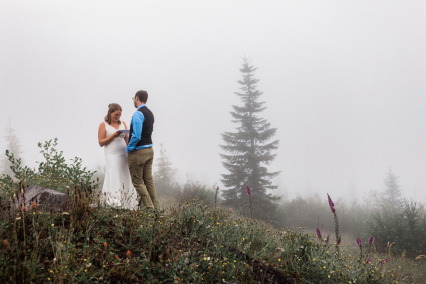 Bride and Groom read vows in the middle of the summer wildflowers at Mount St. Helens. Photographed by PNW Elopement Photographer, Megan Montalvo Photography. 