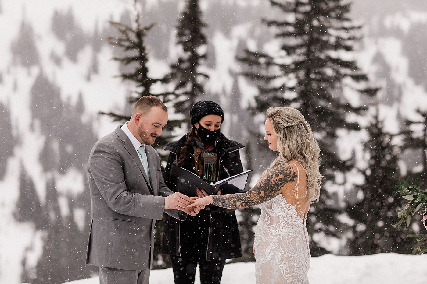 Ring exchange in the snow during elopement ceremony at Paradise at Mt Rainier. Photo by Megan Montalvo Photography.