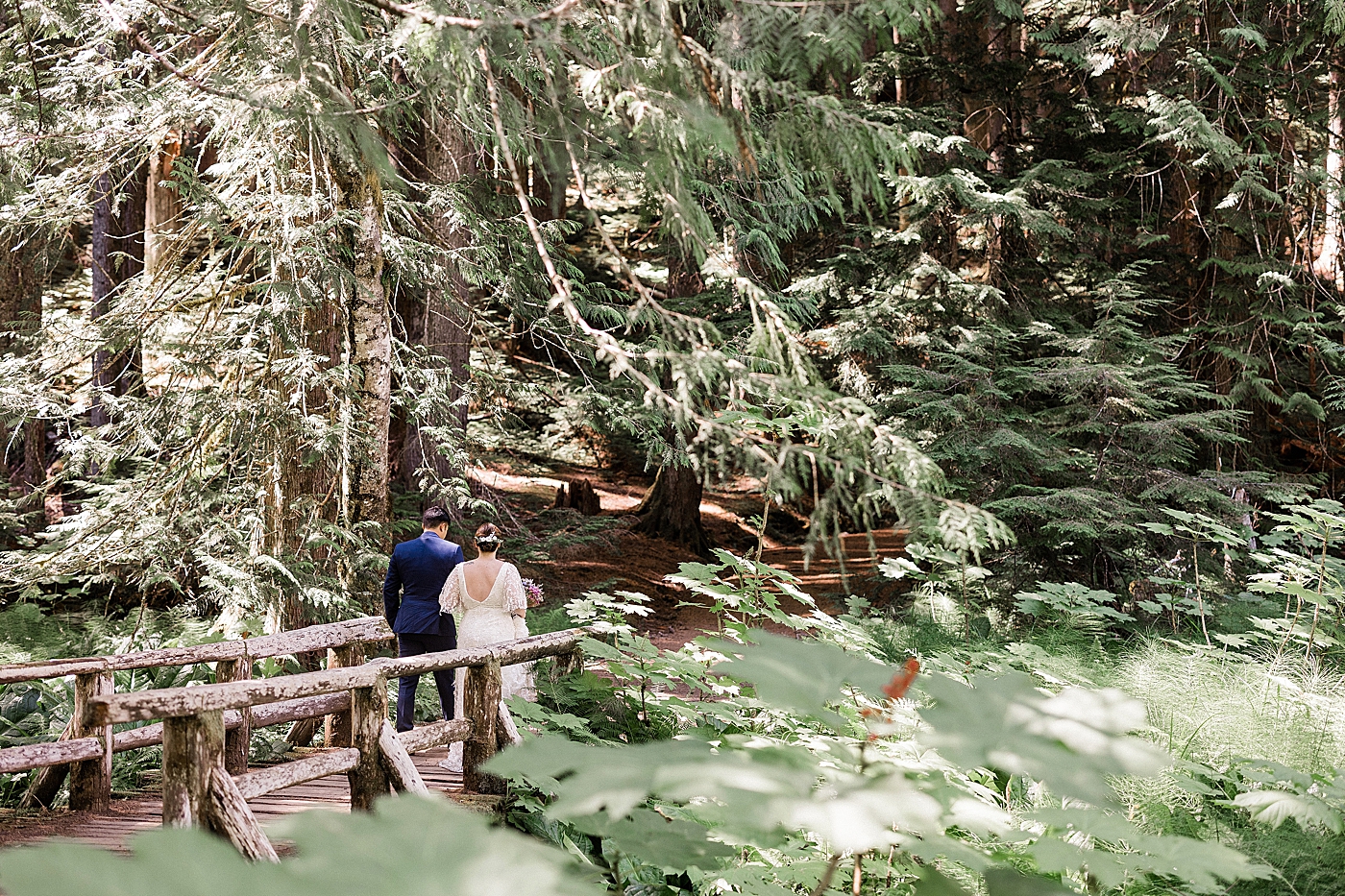Bride and groom walking through the forest at Mt Rainier. Photo by Megan Montalvo Photography.