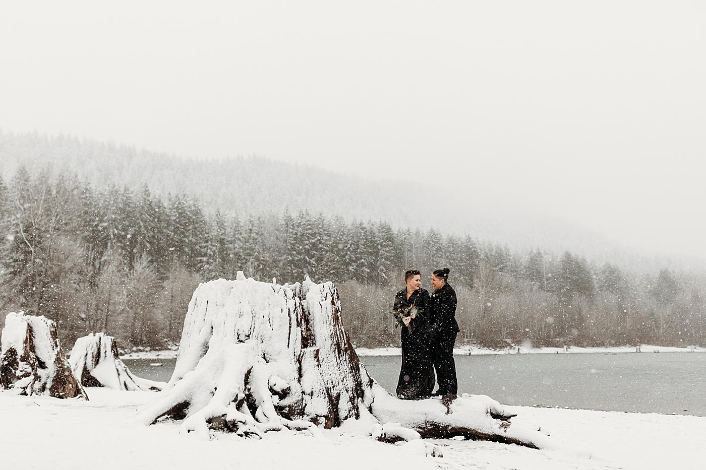 Couple standing in front of Rattlesnake Lake in the snow. Photo by Megan Montalvo Photography.