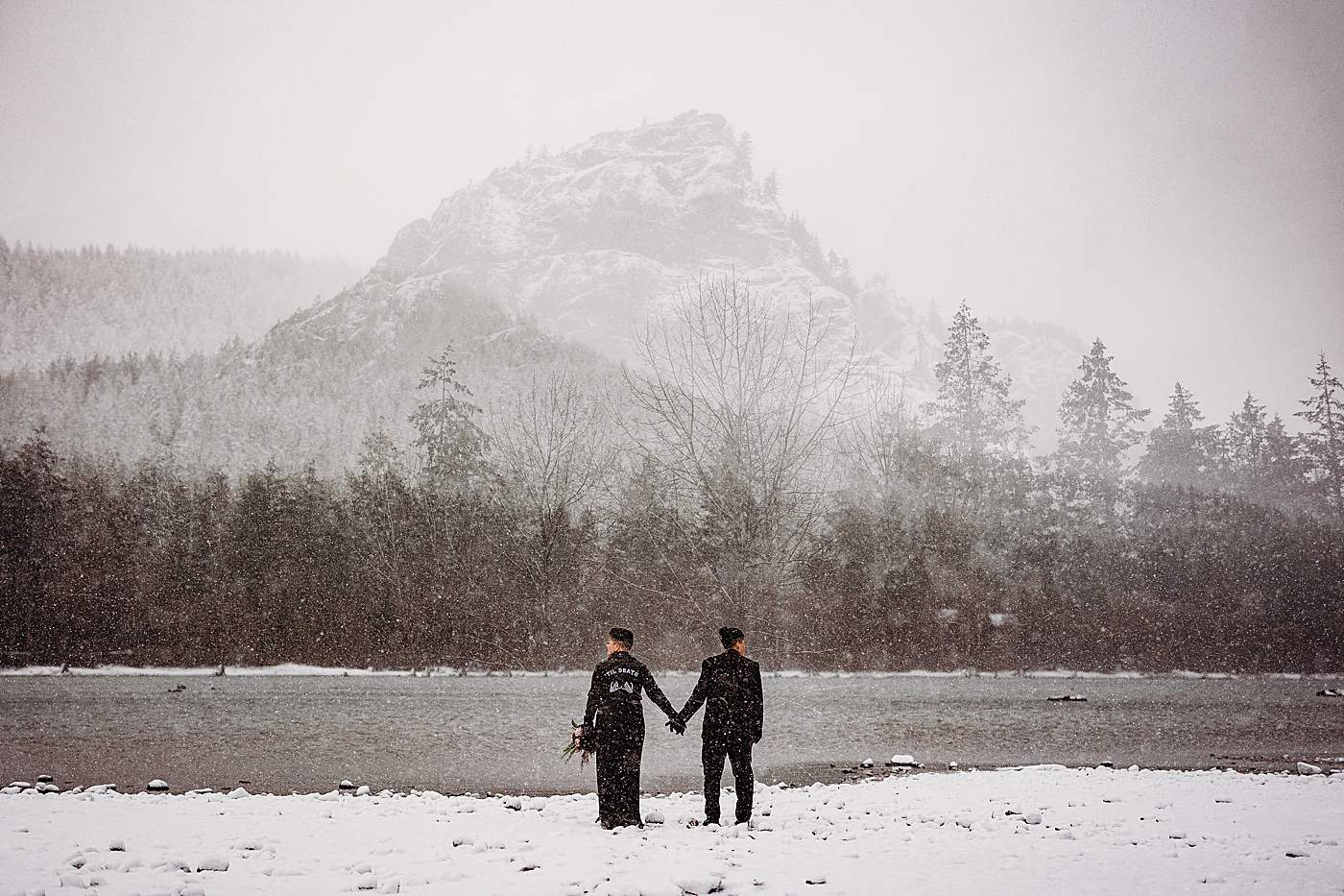 Couple holding hands looking off towards the mountains. Photo by Megan Montalvo Photography.