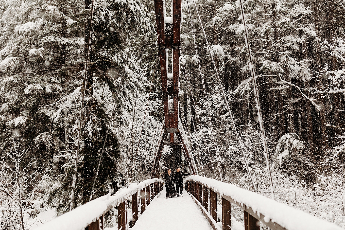 Couple walking on Middle Fork bridge covered in snow. Photo by Megan Montalvo Photography.