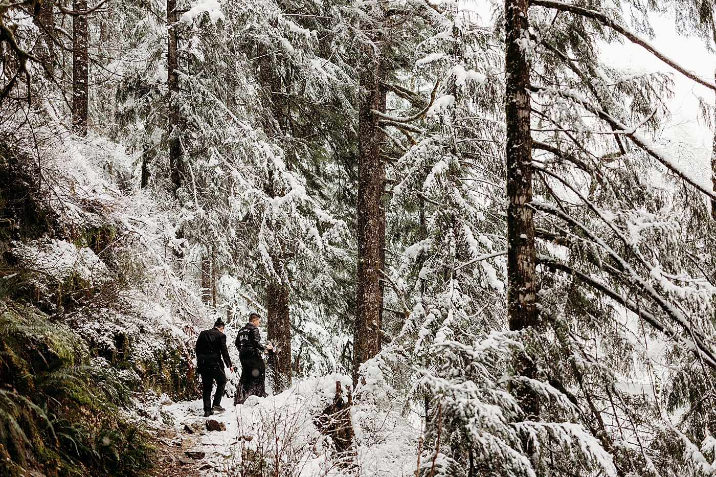 Couple hiking through the mountains for snowy elopement. Photo by Megan Montalvo Photography.