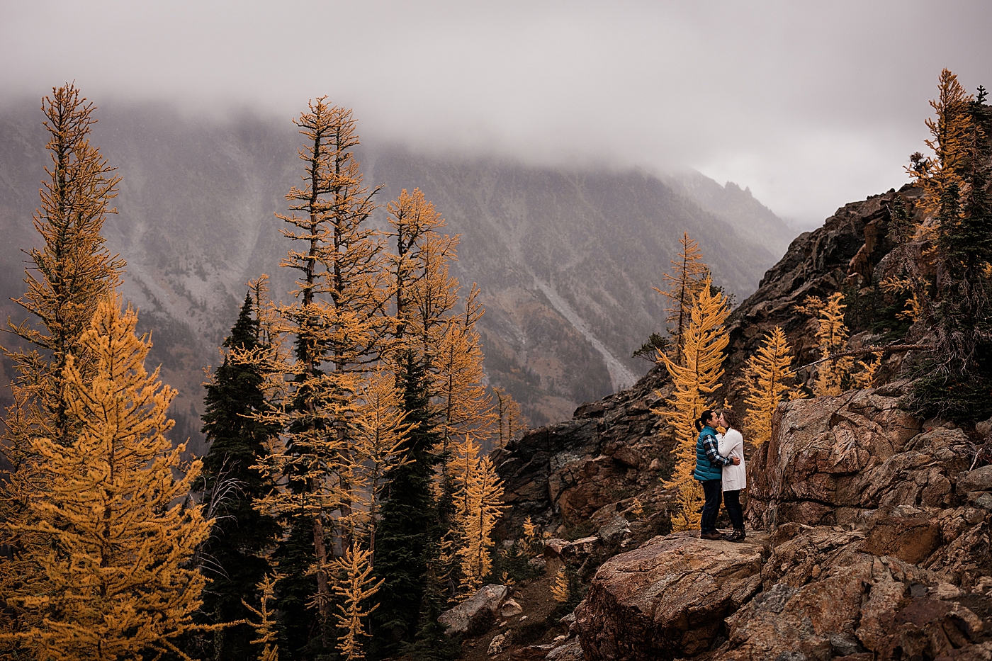Couple standing in the midst of larches at Lake Ingalls. Photo by Megan Montalvo Photography.