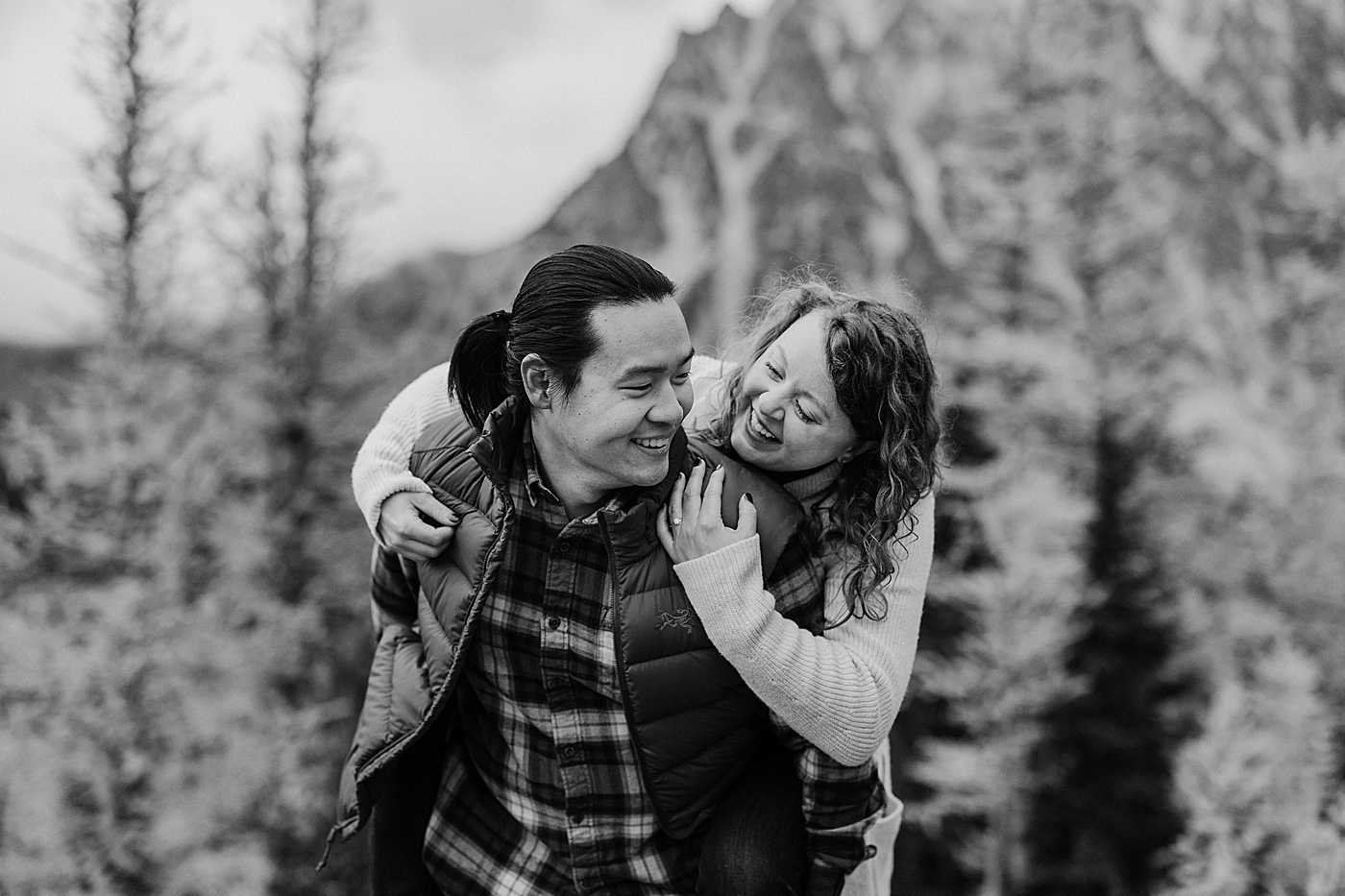 Couple giving piggy-back ride during engagement session in the larches in WA. Photo by Megan Montalvo Photography.