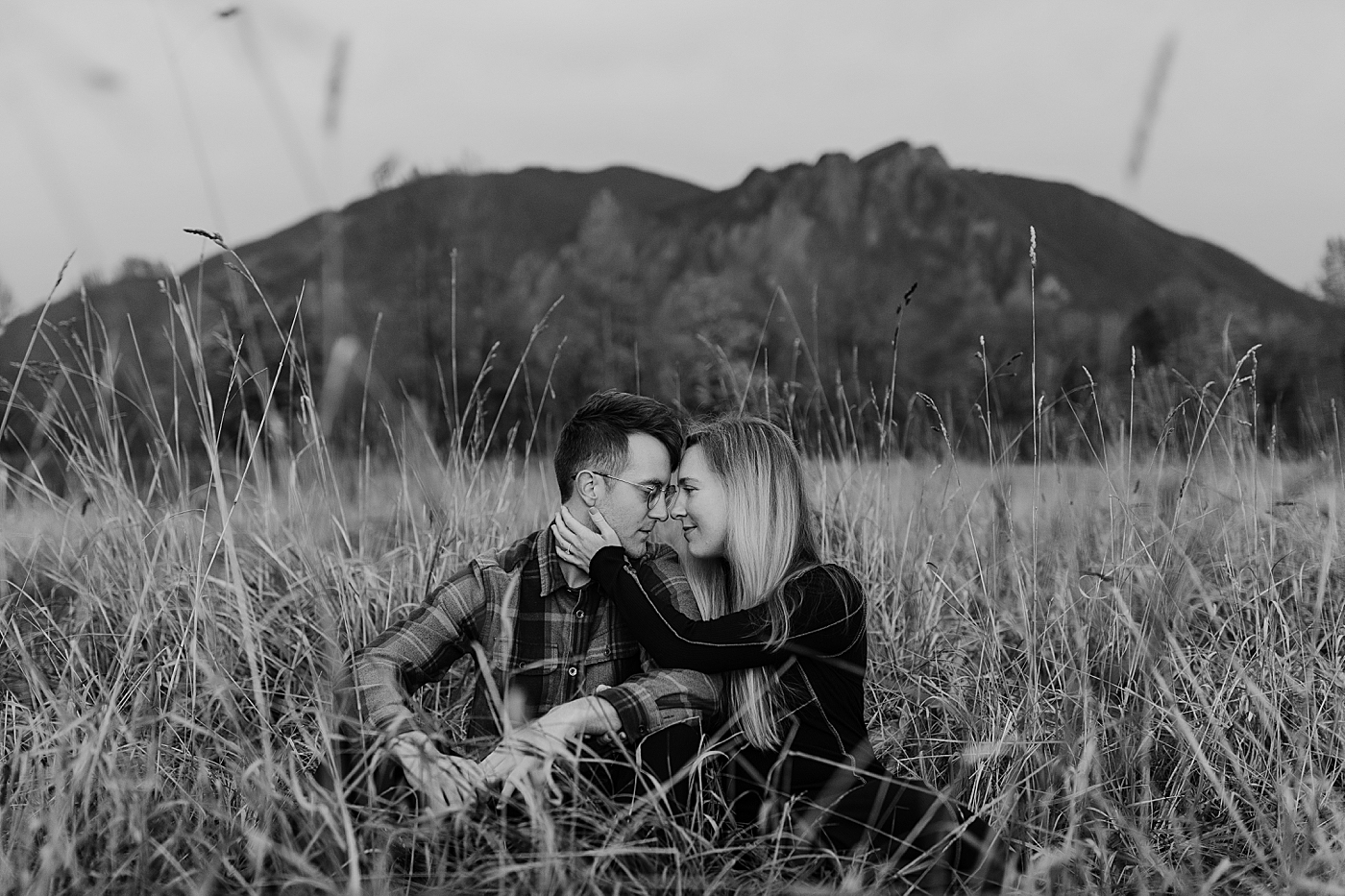 Couple sitting in grass in front of Mount Si. Photo by Megan Montalvo Photography.