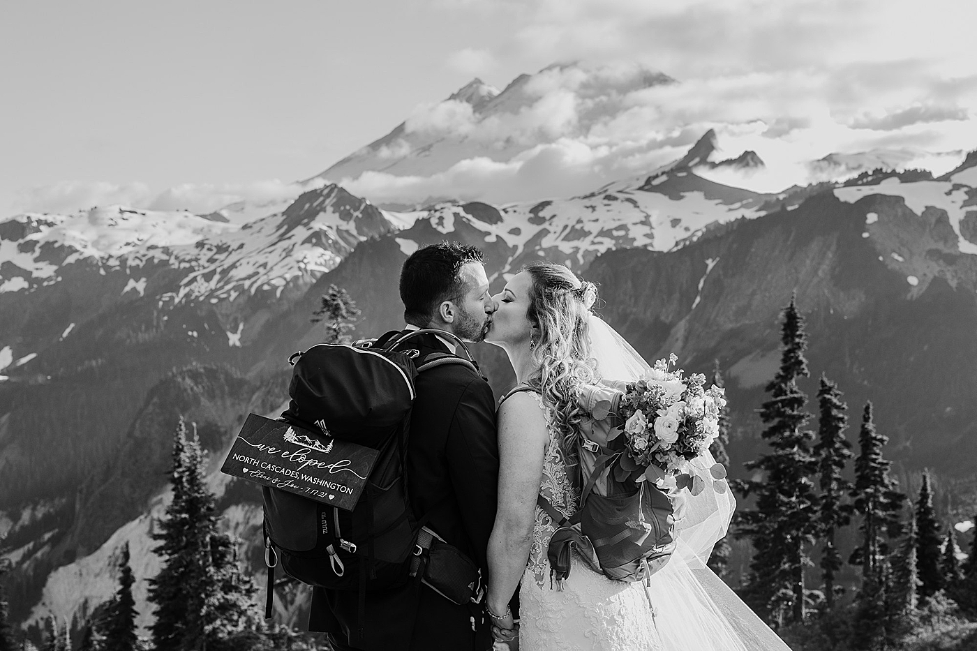 Couple at the top of Artist Point with elopement sign. Photo by Megan Montalvo Photography.
