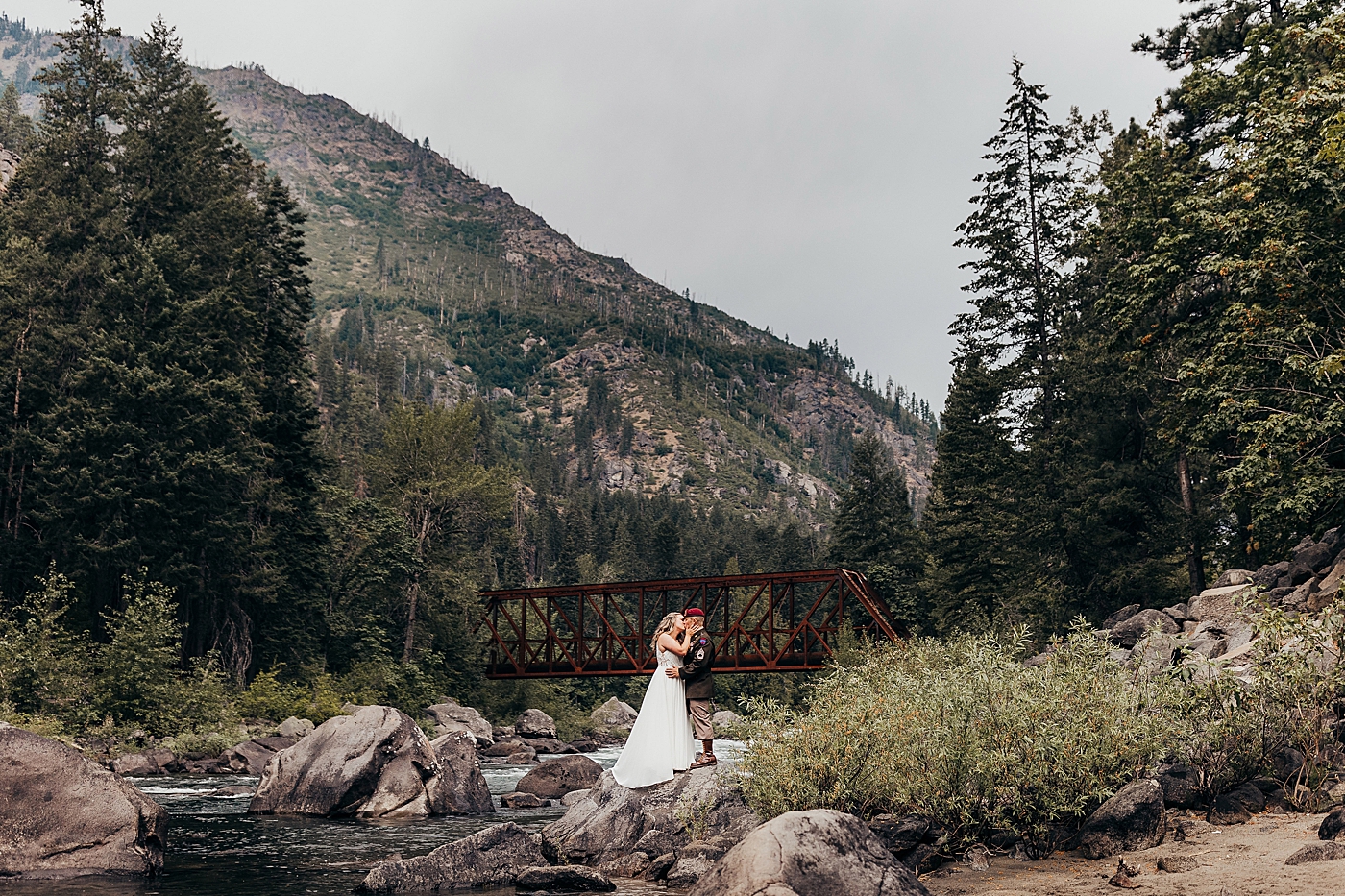 Bride and groom standing on a rock kissing during elopement in Leavenworth. Photo by Megan Montalvo Photography.