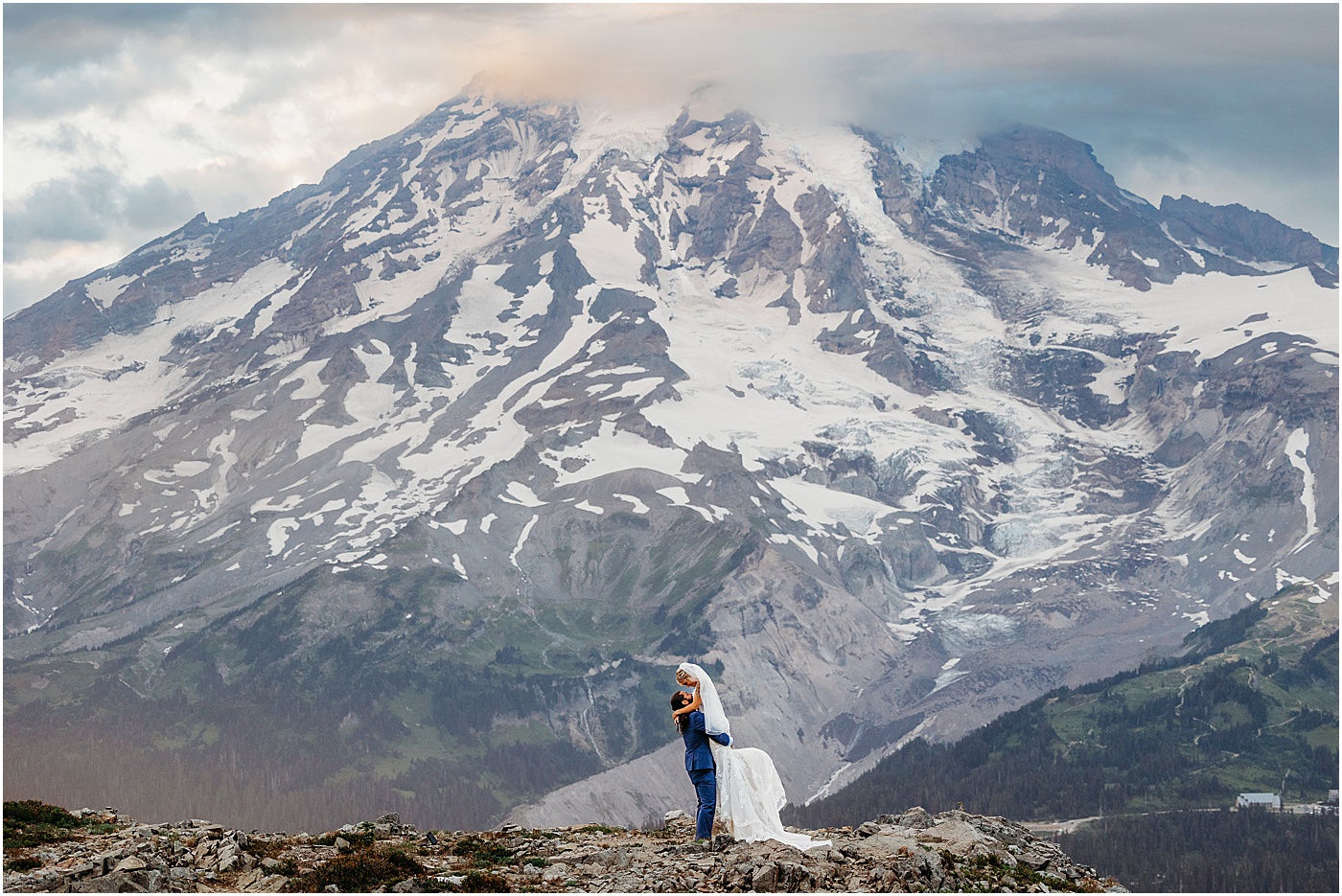 Groom holding bride up in the air with snow-capped Mt. Rainier in the background | Photo by Megan Montalvo Photography