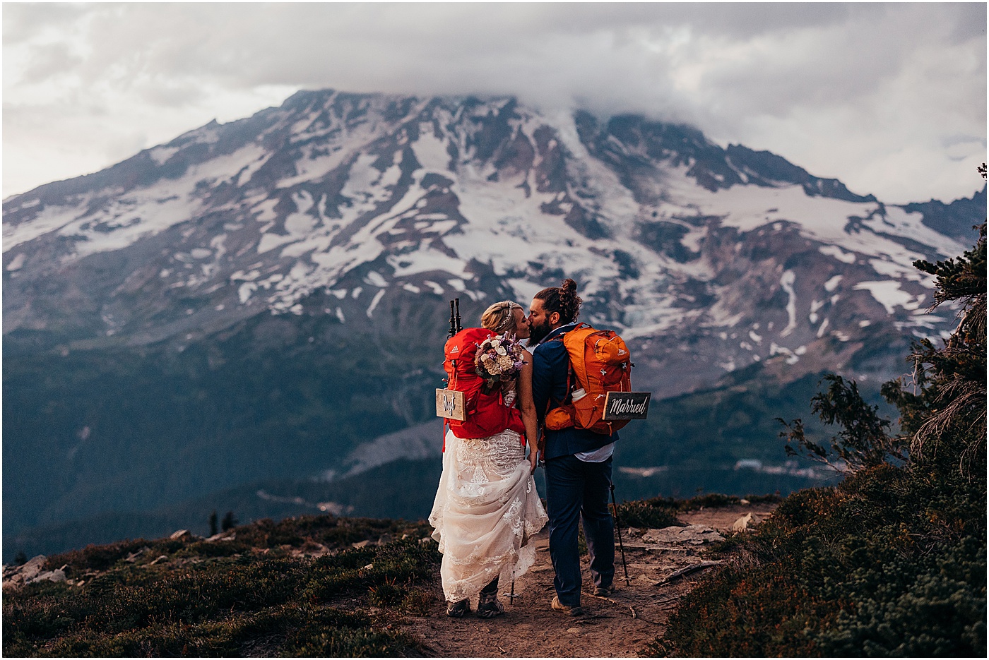 Couple with just married signs standing in front of Mount Rainier | Photo by Megan Montalvo Photography