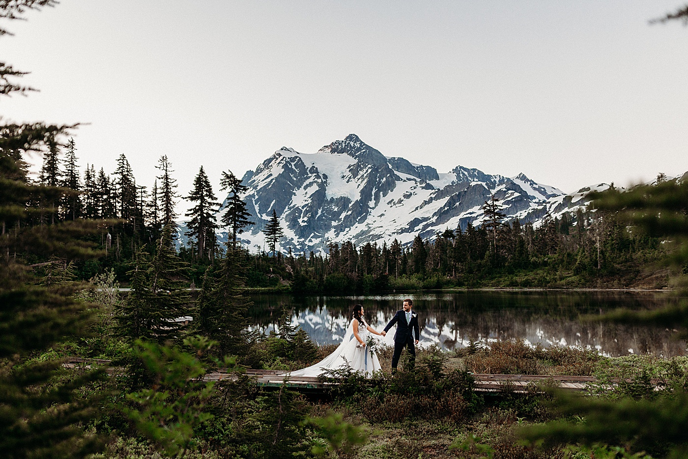 Groom leading the bride in front of scenic picture lake