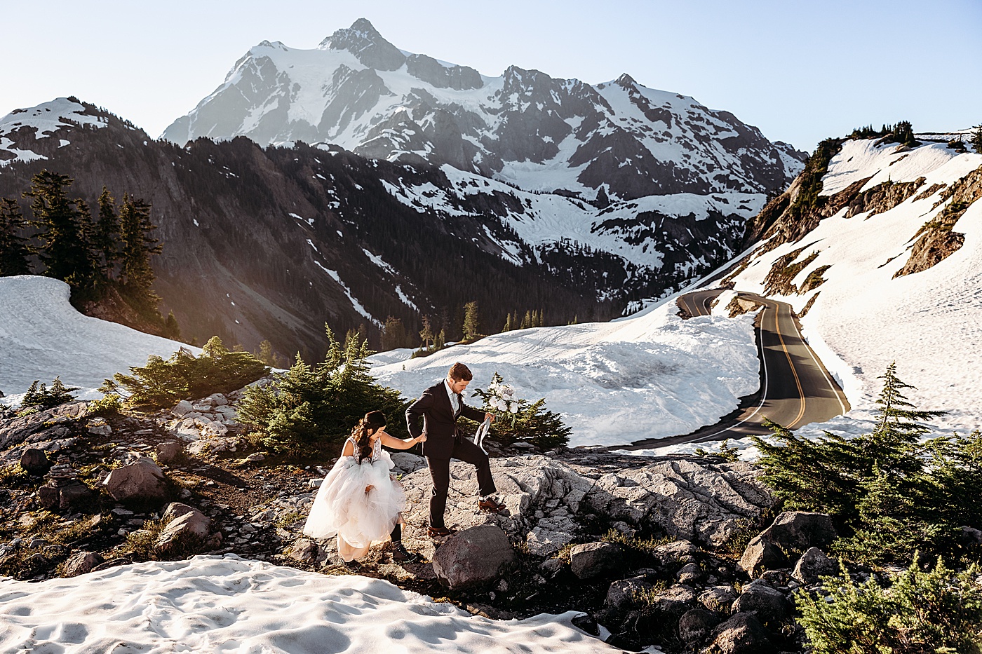 Bride and groom walking over rocks and snow | Megan Montalvo Photography