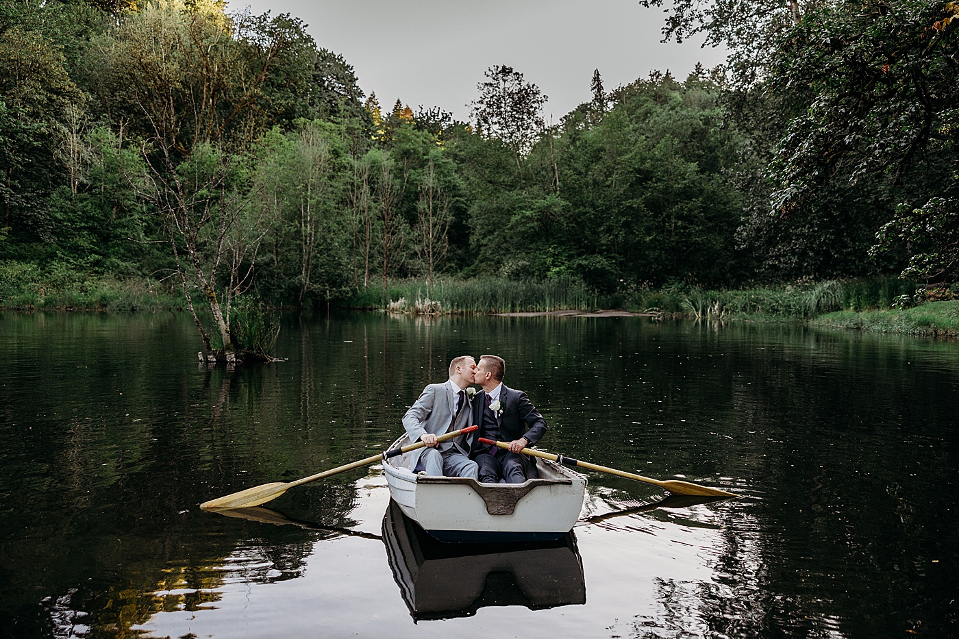 Grooms kissing while sitting on boat at Sanders Estate | Megan Montalvo Photography