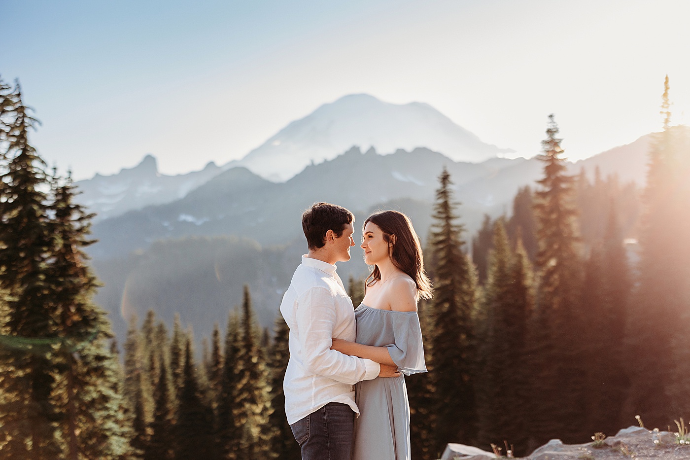 Couple looking at each other with views of the mountains in the background at Mt. Rainier | Photo by Megan Montalvo Photography