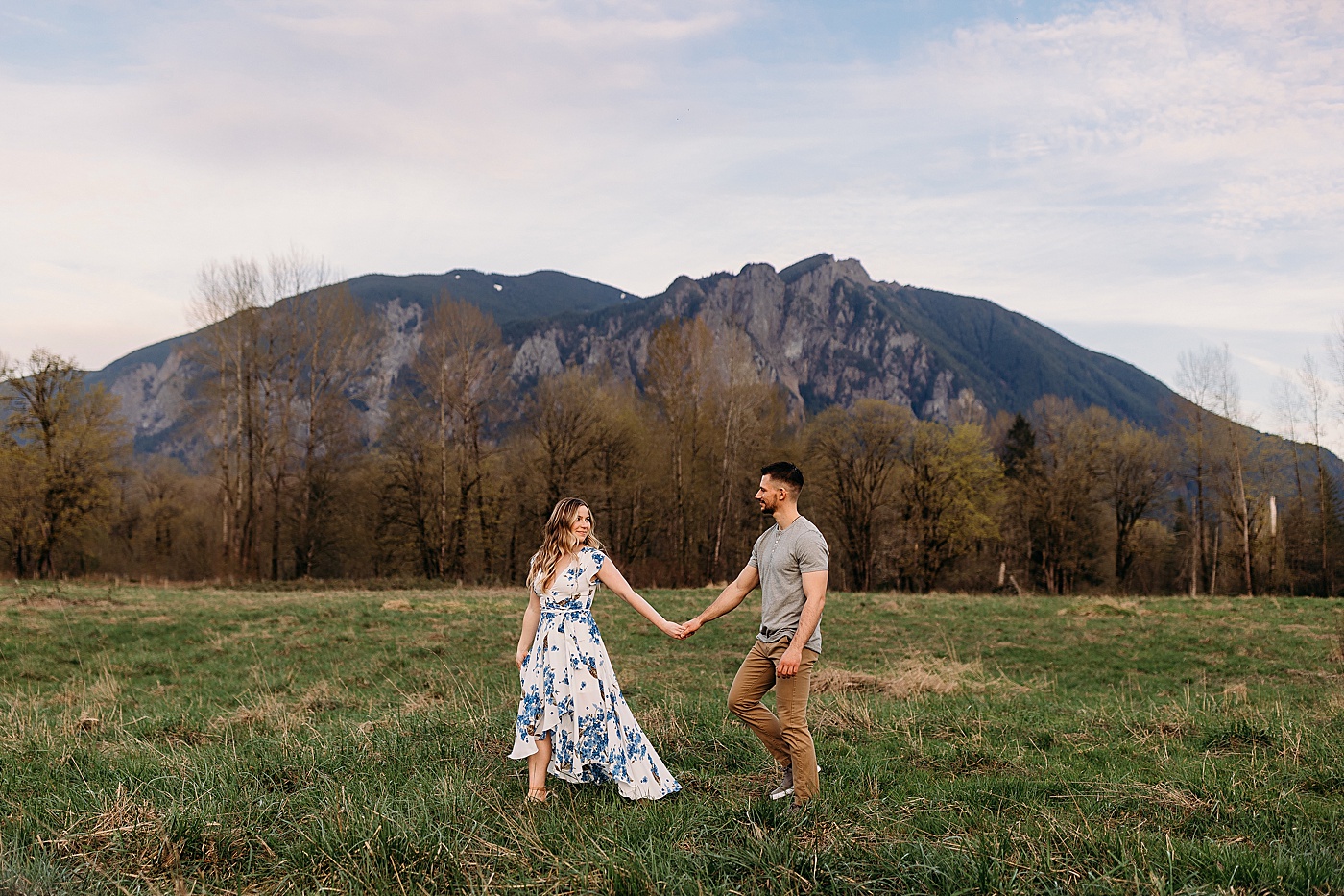 Couple walking through field during engagement photos in North Bend, WA | Photo by Megan Montalvo Photography