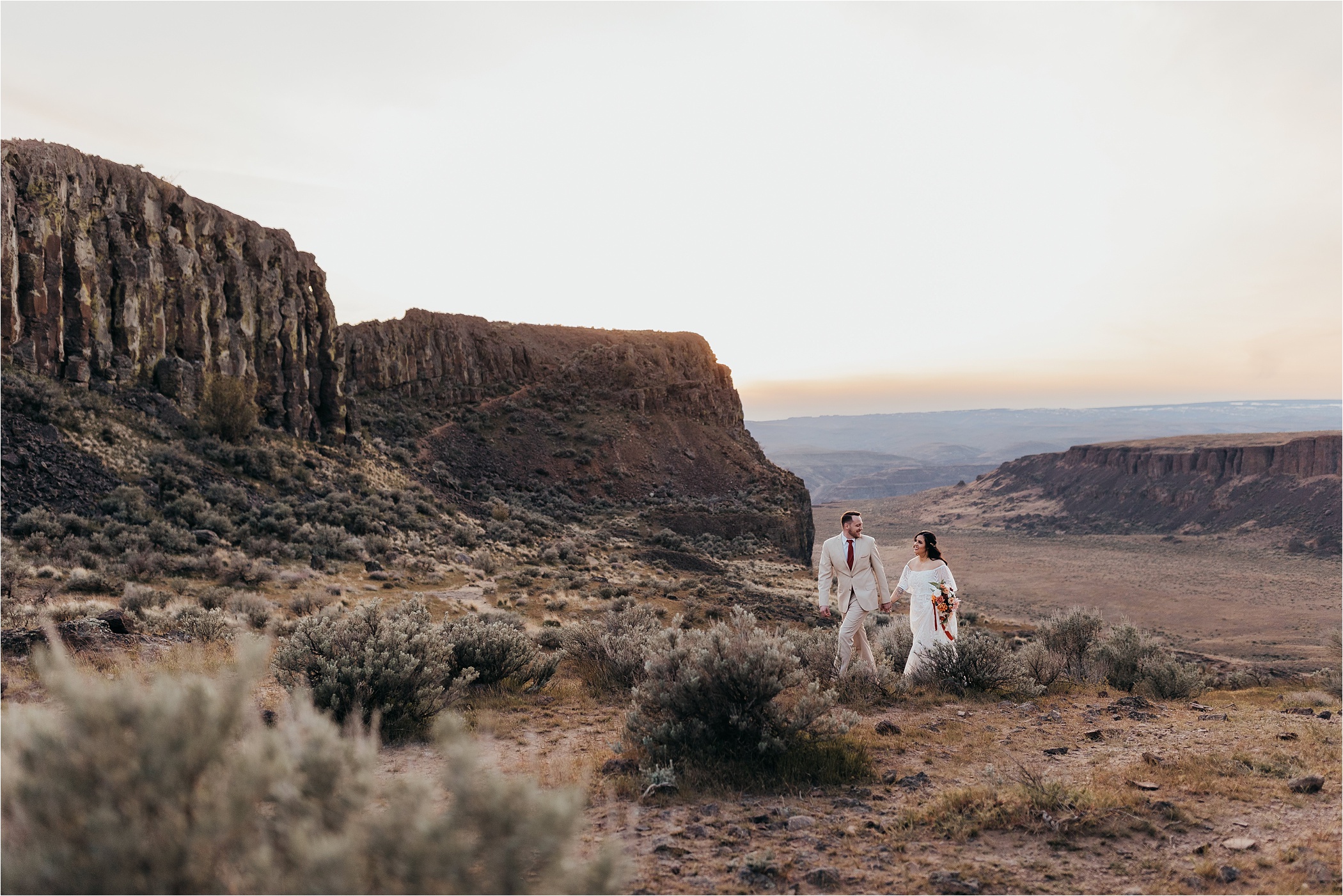 Couple holding hands walking in front of a desert canyon