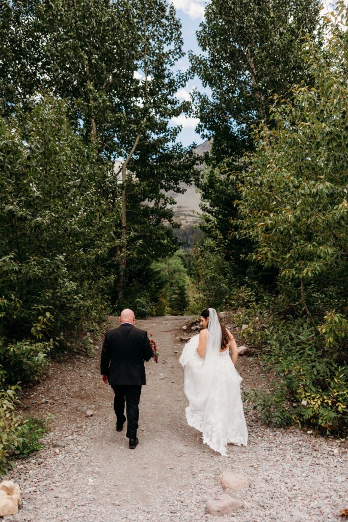 bride and groom walk through woods together