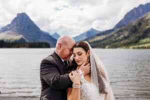 groom holds brides face in front of prayer lake