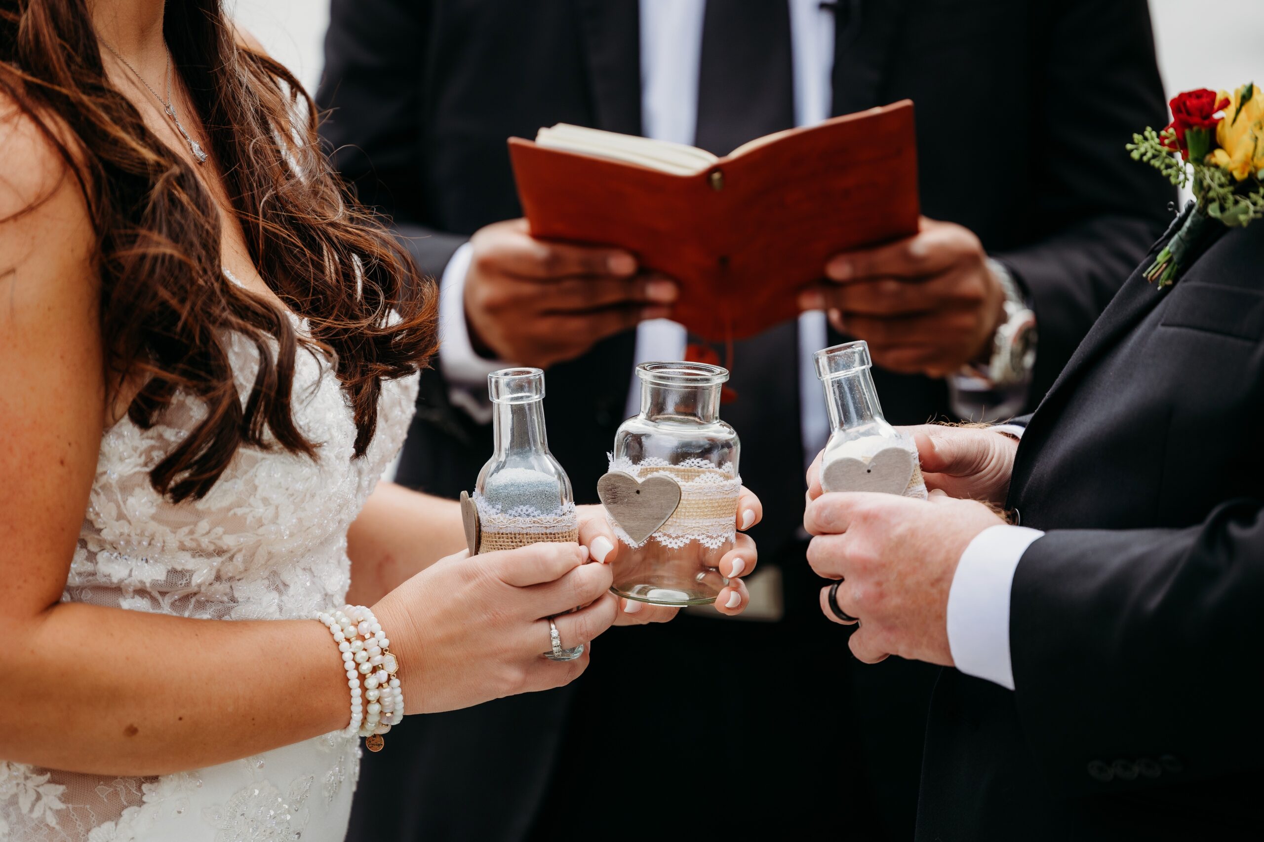 groom and bride hold bottles filled with sand