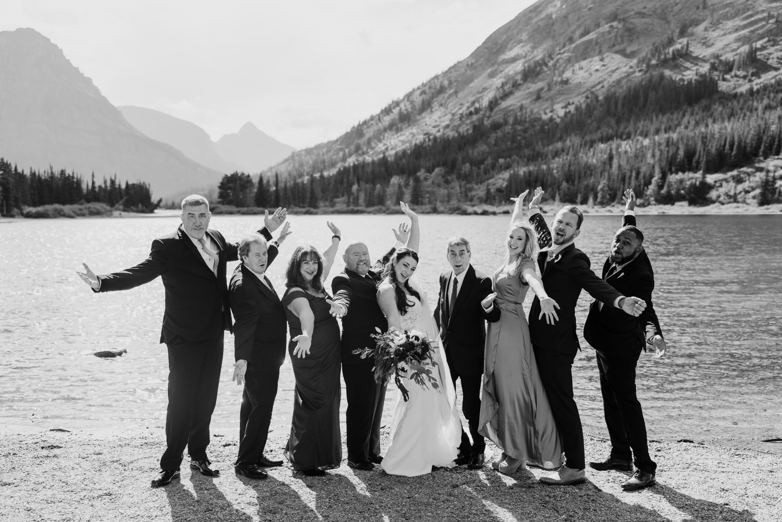 small wedding group holds arms up in a cheer