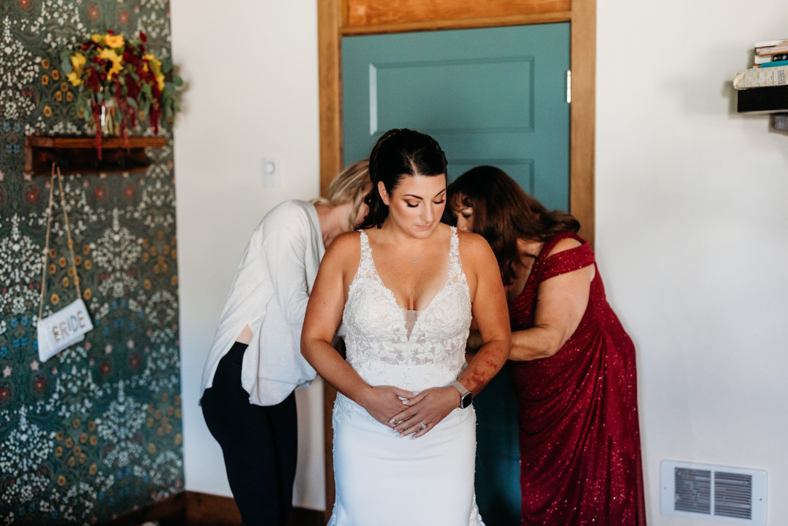 bride is helped into her dress by mom and friend