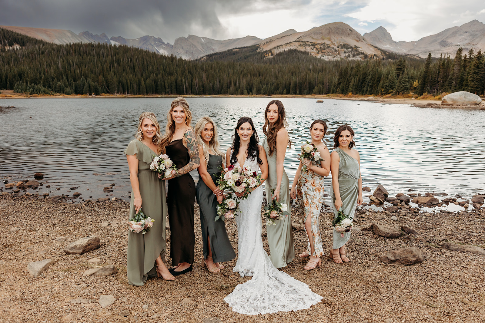 bride with her bridesmaids in front of a lake