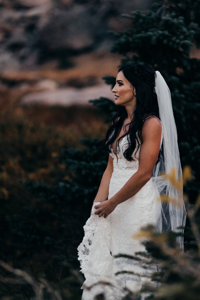 bride holds wedding dress and looks out 