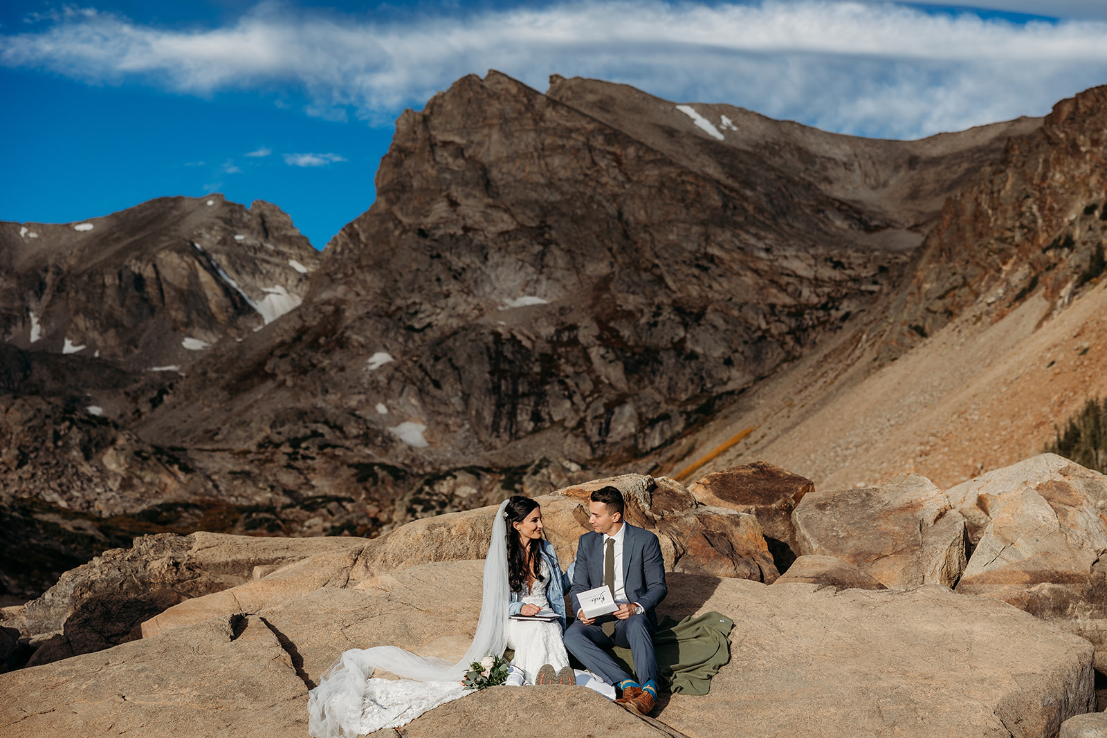 bride and groom sit on rock together
