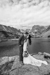 bride and groom kiss in front of lake