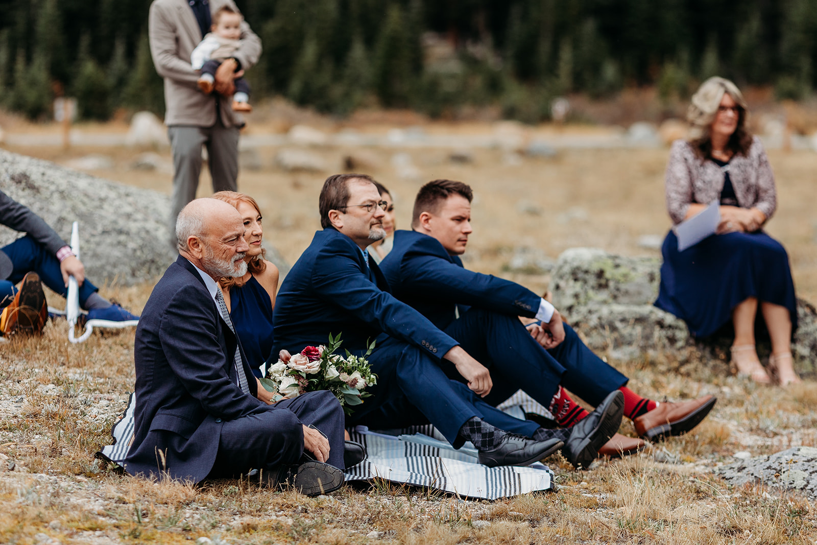 wedding guests sit on ground during colorado elopement