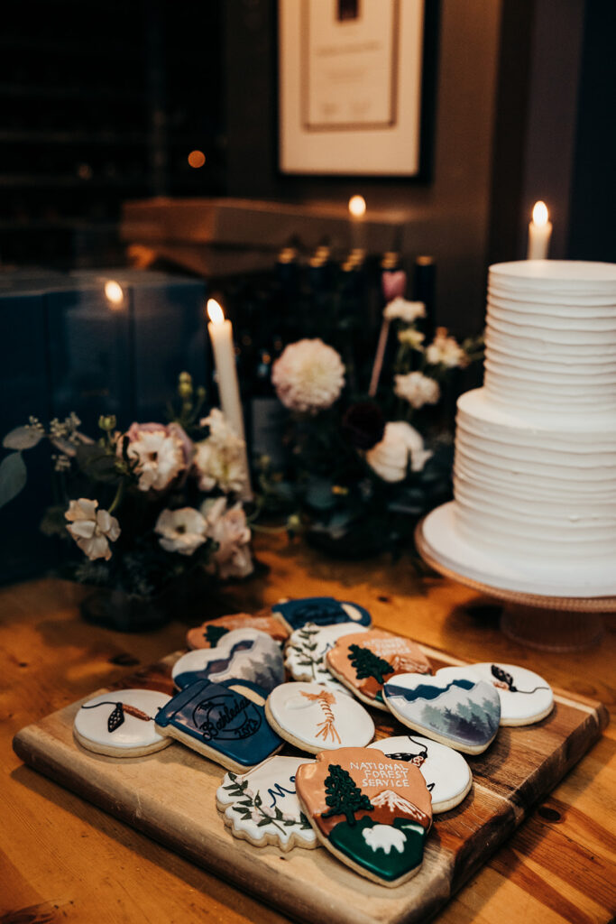 white wedding cake next to decorated cookies