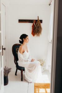 bride sits in antique chair and stares out window