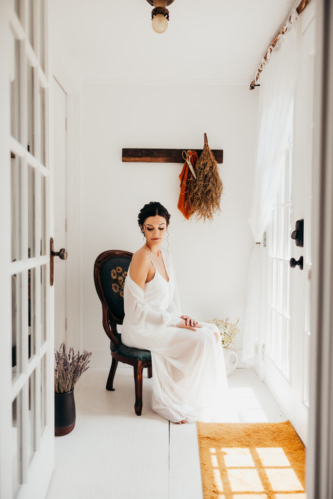 bride sits in antique chair and looks at shoulder