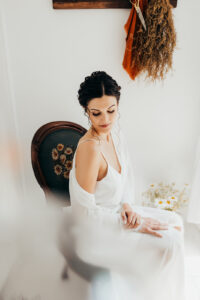 bride sits in antique chair looking down at her shoulder