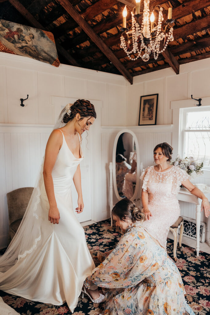 bride gets help putting her shoes on