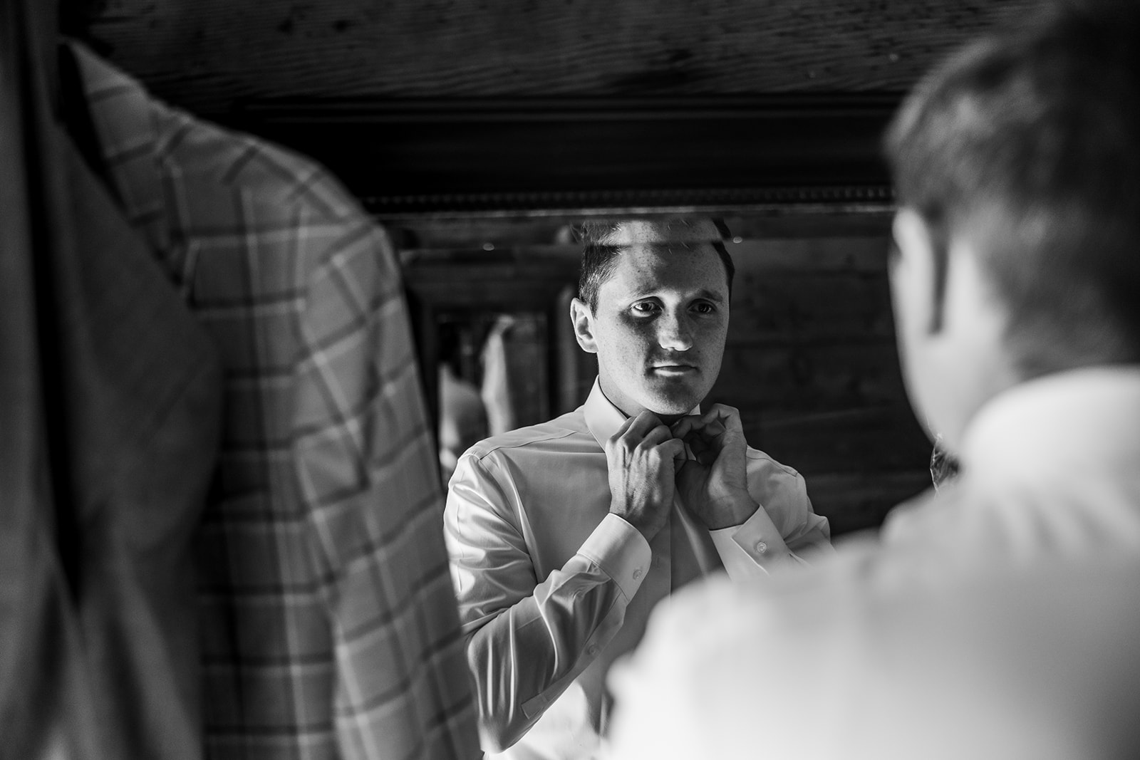 groom looks in mirror as he gets ready