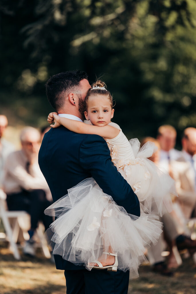 groom holds little girl during ceremony
