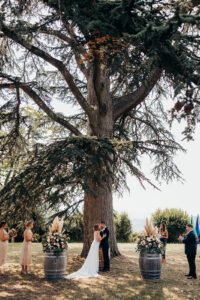 bride and groom kiss under giant tree during ceremony