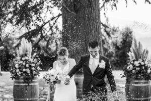 bride and groom walk up aisle under a cloud of confetti