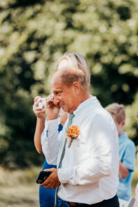 father of bride wipes a tear from his cheek