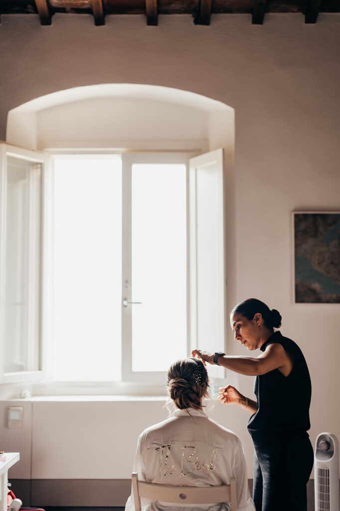 bride gets her hair done in window light