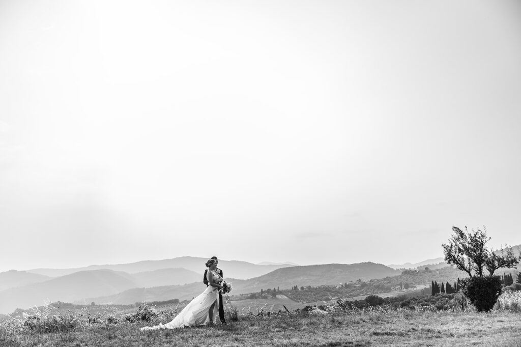 bride and groom embrace and stand in front of field