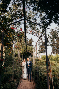 bride and groom walk through trellis with plants all over it