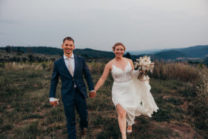 bride and groom walk through field together