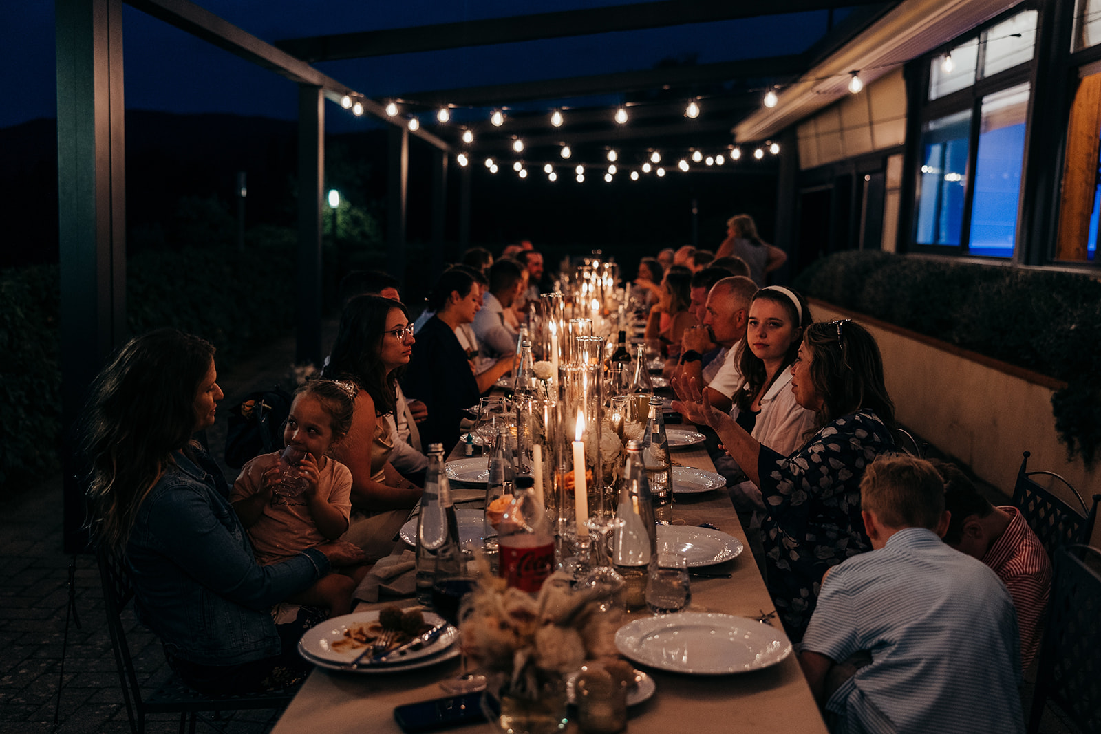 wedding guests sit at a long table lit with candles