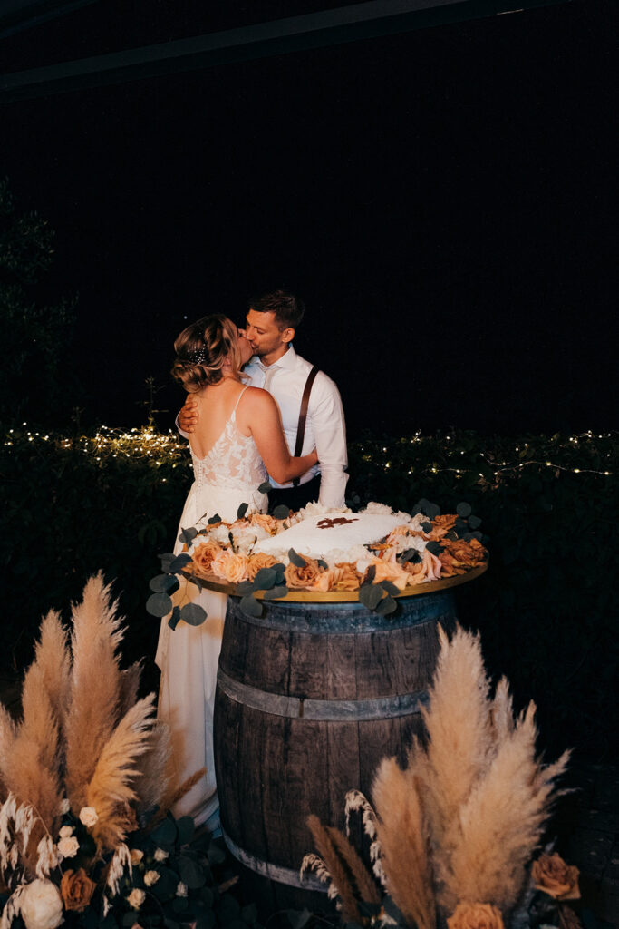 bride and groom kiss behind their cake