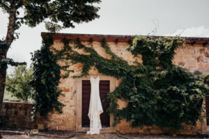 wedding dress hangs on door with vines growing on the side